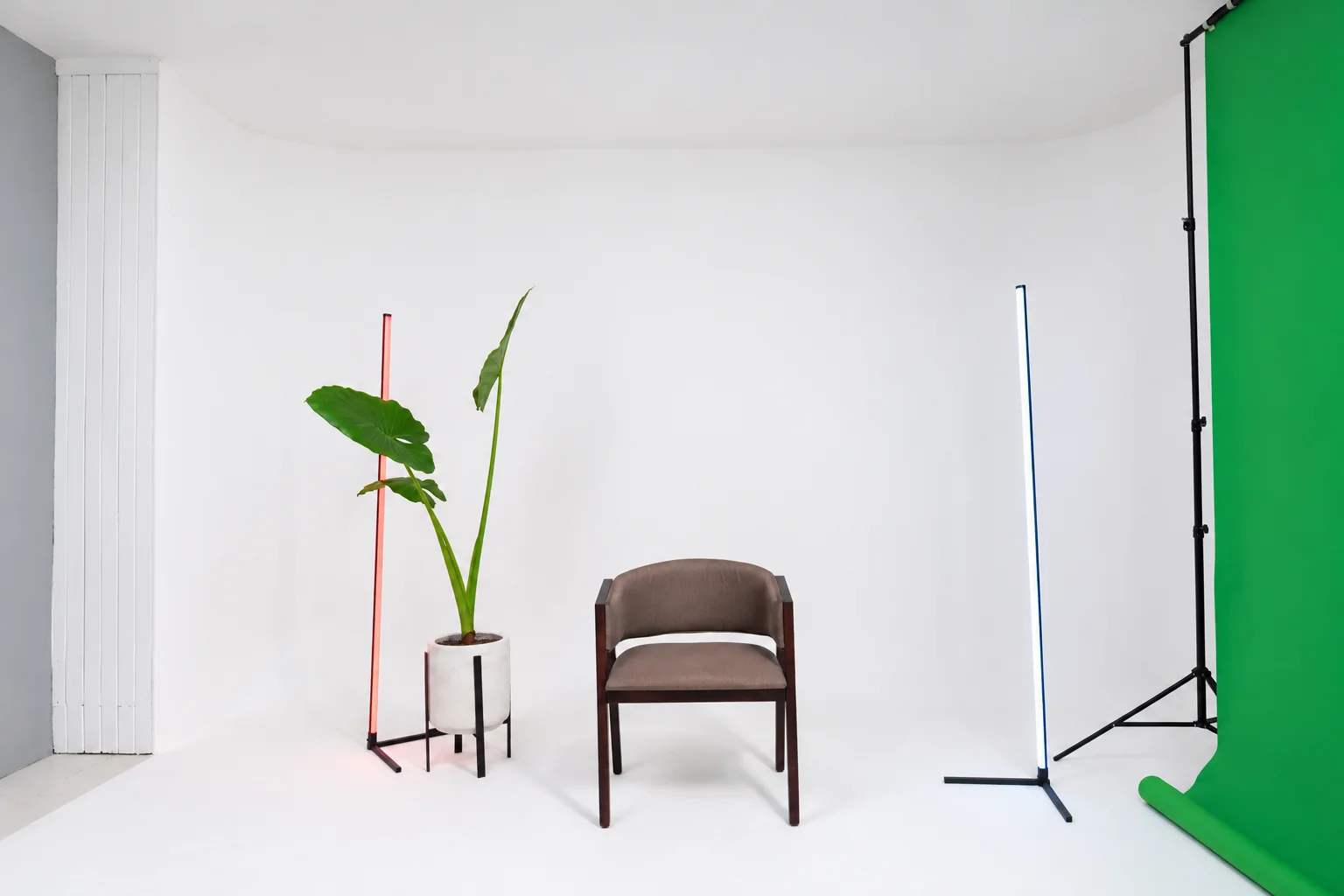 Ciclorama real de Ochenta & Ocho con silla, planta y tubos de luz junto al croma; iluminación y limpieza retocadas con IA.