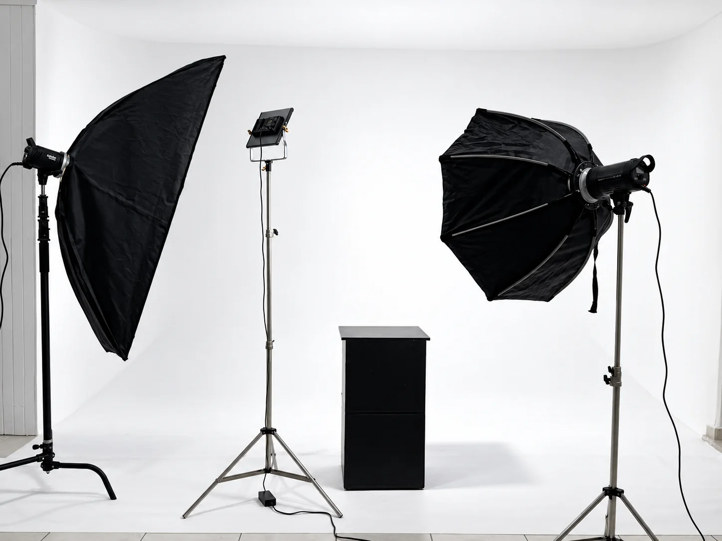 Dos softboxes y una luz central montados frente al ciclorama para preparar una sesión de fotografía.